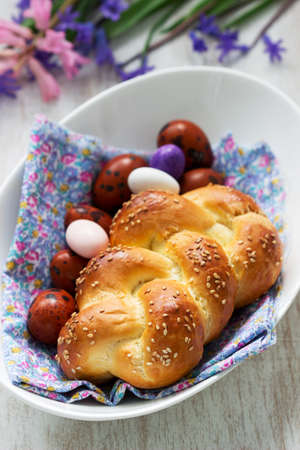 Easter bun, colored eggs and flowers on a white background. Selective focus.