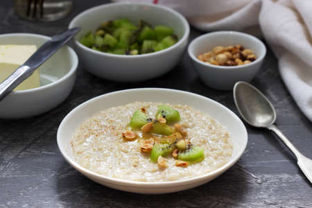 Oatmeal breakfast with butter, kiwi, hazelnuts and cinnamon. Selective focus.の写真素材