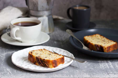 Banana muffin with candied ginger and raisins and drinks on a gray background. Selective focus.