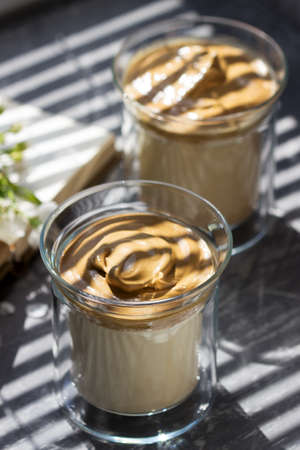 Dalgona Coffee in transparent glasses on a windowsill illuminated by sunlight. Selective focus.の写真素材