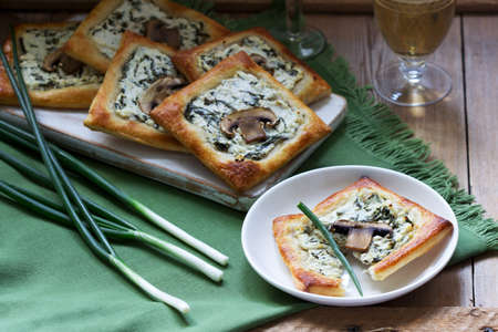 Puffs with cheese, spinach and mushrooms, served with wine and green onions. Rustic style, selective focus.の写真素材