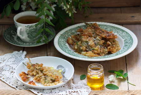 Robinia fritters served with tea and honey on a wooden table. Rustic style.の写真素材