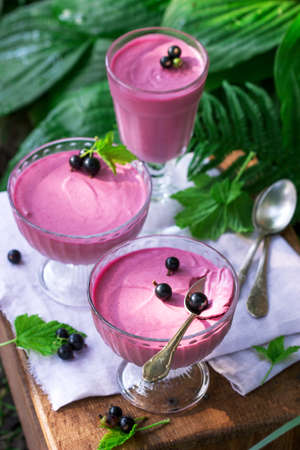 Berry mousse in glass vases on a wooden background in the garden. Selective focus.の写真素材