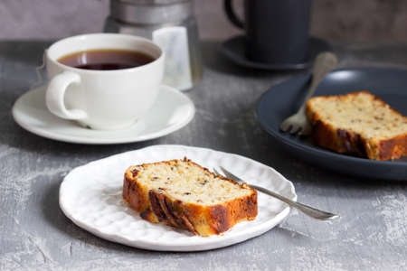 Banana muffin with candied ginger and raisins and drinks on a gray background. Selective focus.