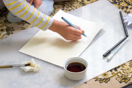 The girl at home draws with tea on watercolor paper. Selective focus.