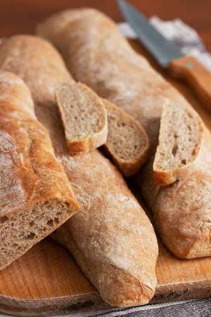 Baguette and baguette slices on a wooden table.