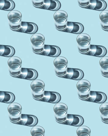 Pattern from glasses with water on a blue background. Ecological concept, space for text.の写真素材