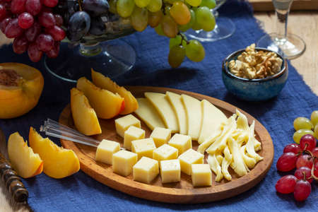 An appetizer of various types of cheese, grapes and walnuts, served with wine. Rustic style.の写真素材