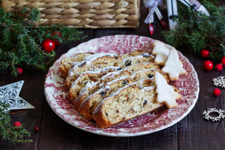 Christmas stollen with dried fruits, nuts and spices, Christmas decorations on a dark wooden background. Rustic style, selective focus.の写真素材