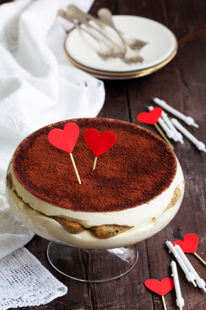 Traditional Italian dessert tiramisu served in a glass vase decorated with paper hearts. Valentine's Day card. Rustic style.の写真素材