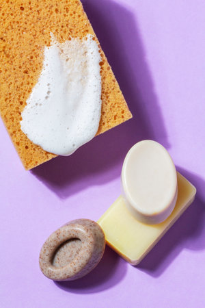 Handmade soap with the addition of coffee and wild herbs and a sponge with foam on a purple background. Selective focus.の写真素材