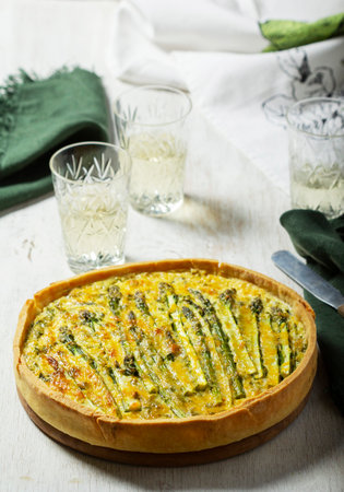 Tart stuffed with asparagus, spinach, chard, cream and cheese, served with white wine. Rustic style, selective focus.の写真素材