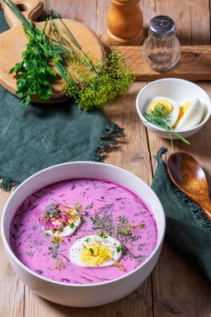 Traditional summer cold beetroot soup with cucumber, egg and sour cream on a wooden background. Rustic style, selective focus.の写真素材