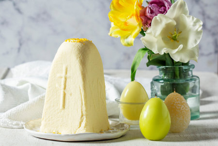 Traditional Slavic Easter dish made from cottage cheese - Paskha, a bouquet of tulips and candles on...