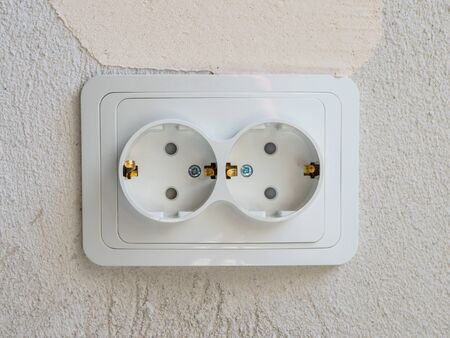 White double electrical socket in the room. Gray concrete wall on the background. Copyspace for...