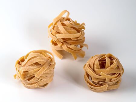 Tagliatelle pasta isolated on white background. Beautiful Italian nest spaghetti with shadows. Copyspace for text.の写真素材