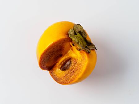 Single persimmon isolated on white background. Fresh fruit of diospyros tree that grows in tropical lands. Copyspace for text.の写真素材