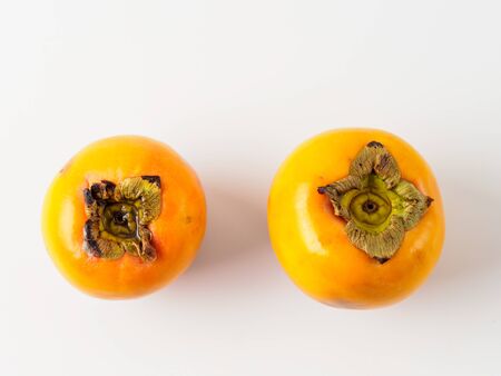 Top view of two persimmon isolated on white background. Fresh fruit of diospyros tree that grows in tropical lands. Copyspace for text.の写真素材