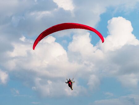 Paraglider is flying in the blue sky. White beautiful cllouds on the background. Copyspace for text.
