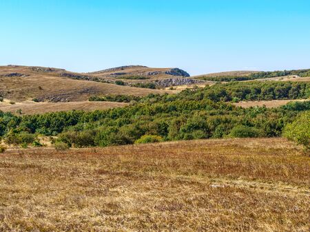 Mountain pasture in autumn sunny day. Beautiful view of plateau yaila in Crimean mountains with yellow grass and blue sky on the background.の写真素材