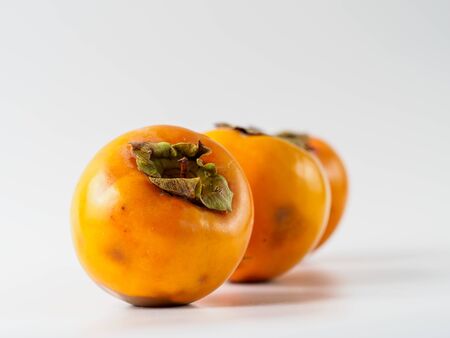 Two persimmon isolated on white background. Fresh fruit of diospyros tree that grows in tropical lands. Copyspace for text.の写真素材