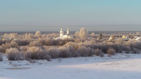 Winter view of Russian village. Beautiful landscape with church and forest on the background.の写真素材