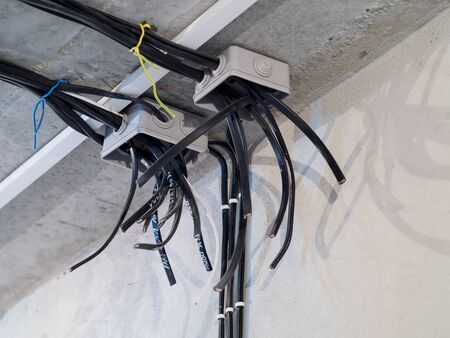 Electric installation on the ceiling. Cable boxes with wires on concrete wall.の写真素材
