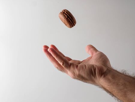 French macaron is falling into man's hand. Isolated on white background. Copyspace for text.の写真素材