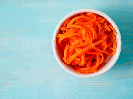 Korean carrot in the bowl on blue wooden background. Copyspace for text.の写真素材