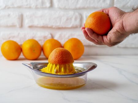 Manual juicer with mans hand holding orange.