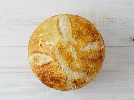 Loaf of bread on wooden background. Top view of natural domestic bakery.