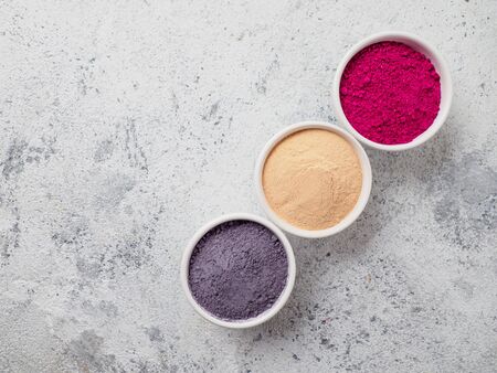 Set of superfoods in white bowls on grey background. Blue butterfly pea, lucuma and dragon fruit powder in the bowls. Copyspace for text.の写真素材
