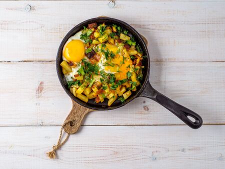 Fried eggs with potato in cast iron pan.の写真素材