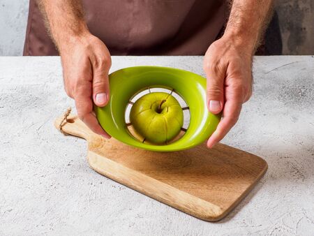 Man cuts apple with slicer. Fruit on cutting board. Space for text.の写真素材