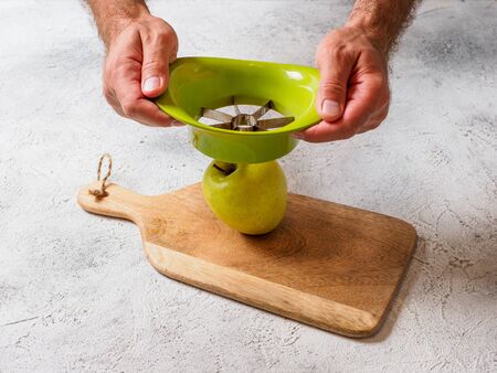 Man cuts apple with slicer. Fruit on cutting board. Space for text.の写真素材