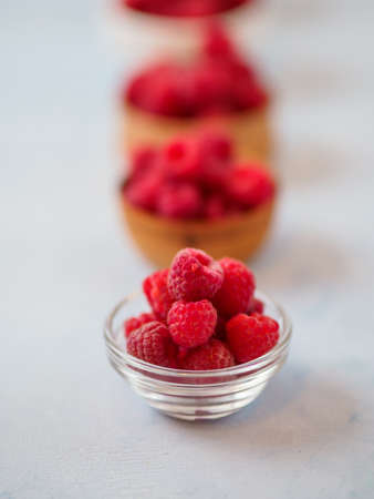 Assorted fresh raspberry in different plates. White background and space for text.の写真素材