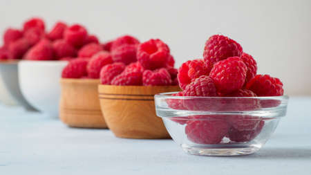 Assorted fresh raspberry in different plates. White background and space for text.の写真素材