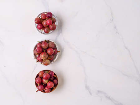 Bowls with fresh gooseberry on white wooden background.の写真素材