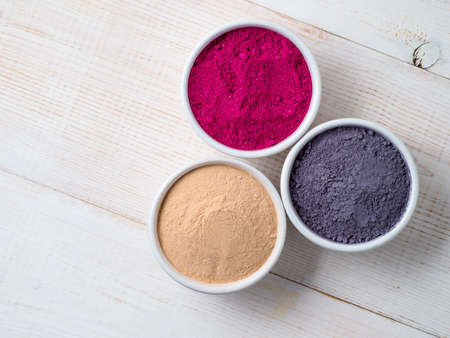 Set of superfoods in white bowls on wooden background.