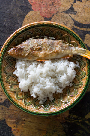fried perch with rice in a beautiful patterned plateの写真素材