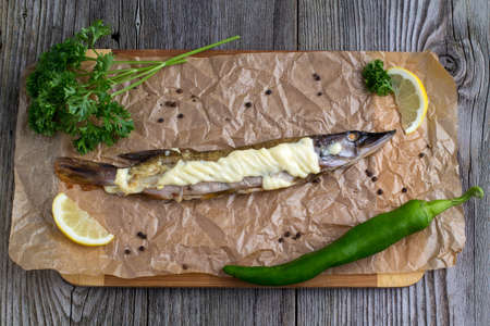 Baked pike wooden on a table with greens and mayonnaise for decorationの写真素材