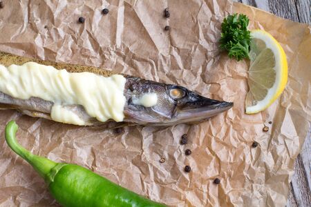 Baked pike wooden on a table with greens and mayonnaise for decorationの写真素材