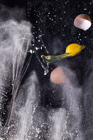 Still life - broken eggs flying between scattered flourの写真素材