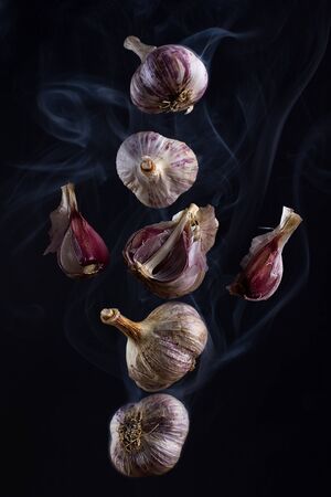 Still life - flying in the smoke garlic on a black backgroundの写真素材