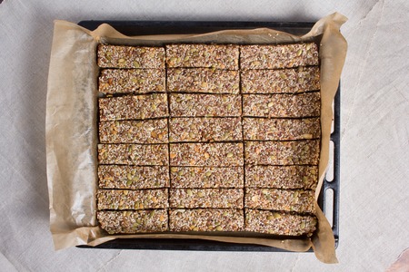 Kozinaki from sesame and peanut seeds of sunflower and pumpkin and other nuts on a black baking sheetの写真素材