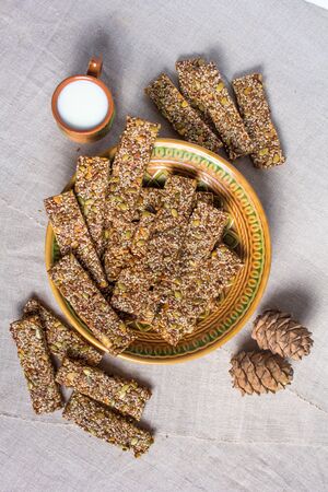 Kozinaki from sesame and peanuts seeds of sunflower and pumpkin and other nuts on a beautiful plate with a cup of milkの写真素材