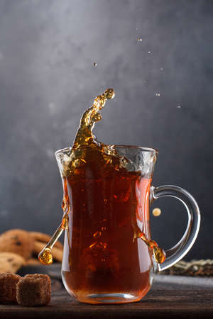 a cap of tea with splashes still life on a black backgroundの写真素材
