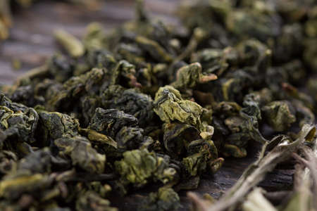 A scattering of green tea leaves on a wooden background