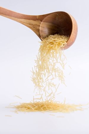 Raw pasta filini on a white background, falling from a wooden spoon. isolatedの写真素材