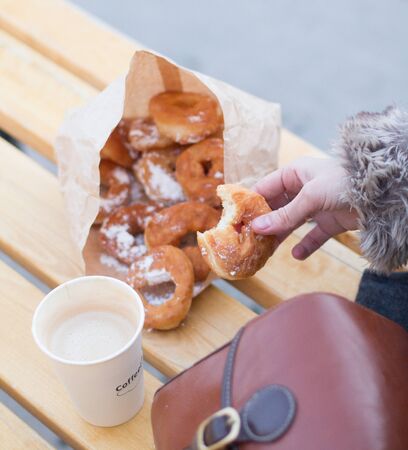 Fast food. Sugar donuts in the hands of the girl. Food on the street - sugar donuts and coffeeの写真素材